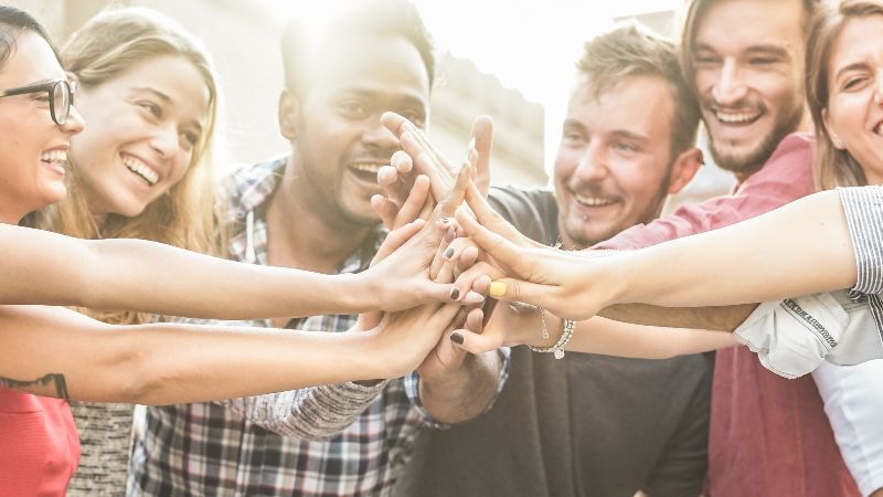 Fröhliche Menschen führen Hände zusammen