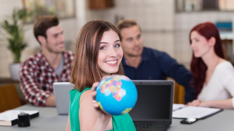 Junge Frau zeigt Weltkugel