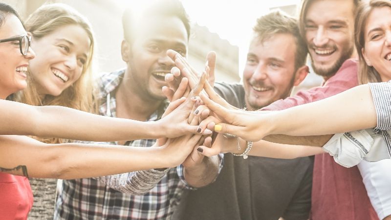 Fröhliche Menschen führen Hände zusammen