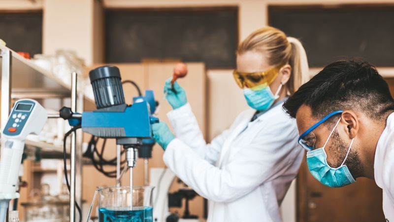 Frau und Mann mit Mundschutz-OP-Masken im Labor