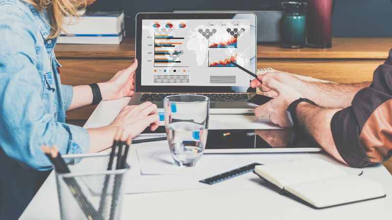 Zwei sitzende Personen sehen Diagramme auf einem Bildschirm