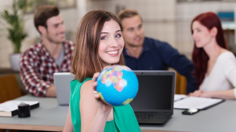 Junge Frau zeigt Weltkugel