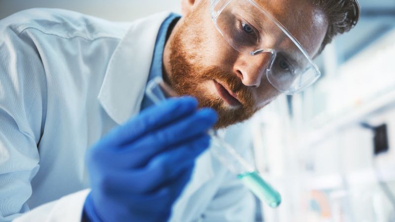 Mann mit Reagenzröhrchen in der Hand im Labor