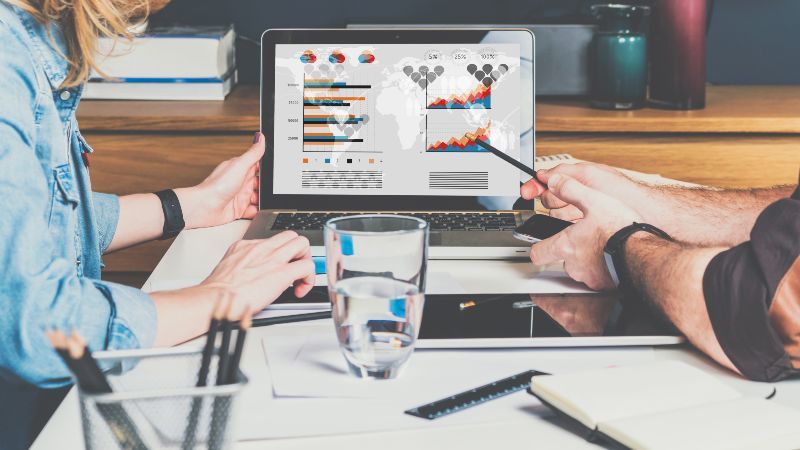 Zwei sitzende Personen sehen Diagramme auf einem Bildschirm