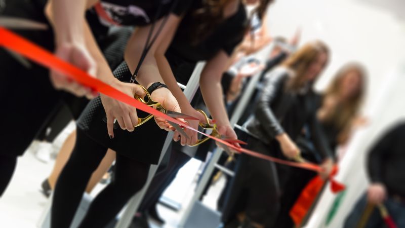 Gruppe zerschneidet rotes Band