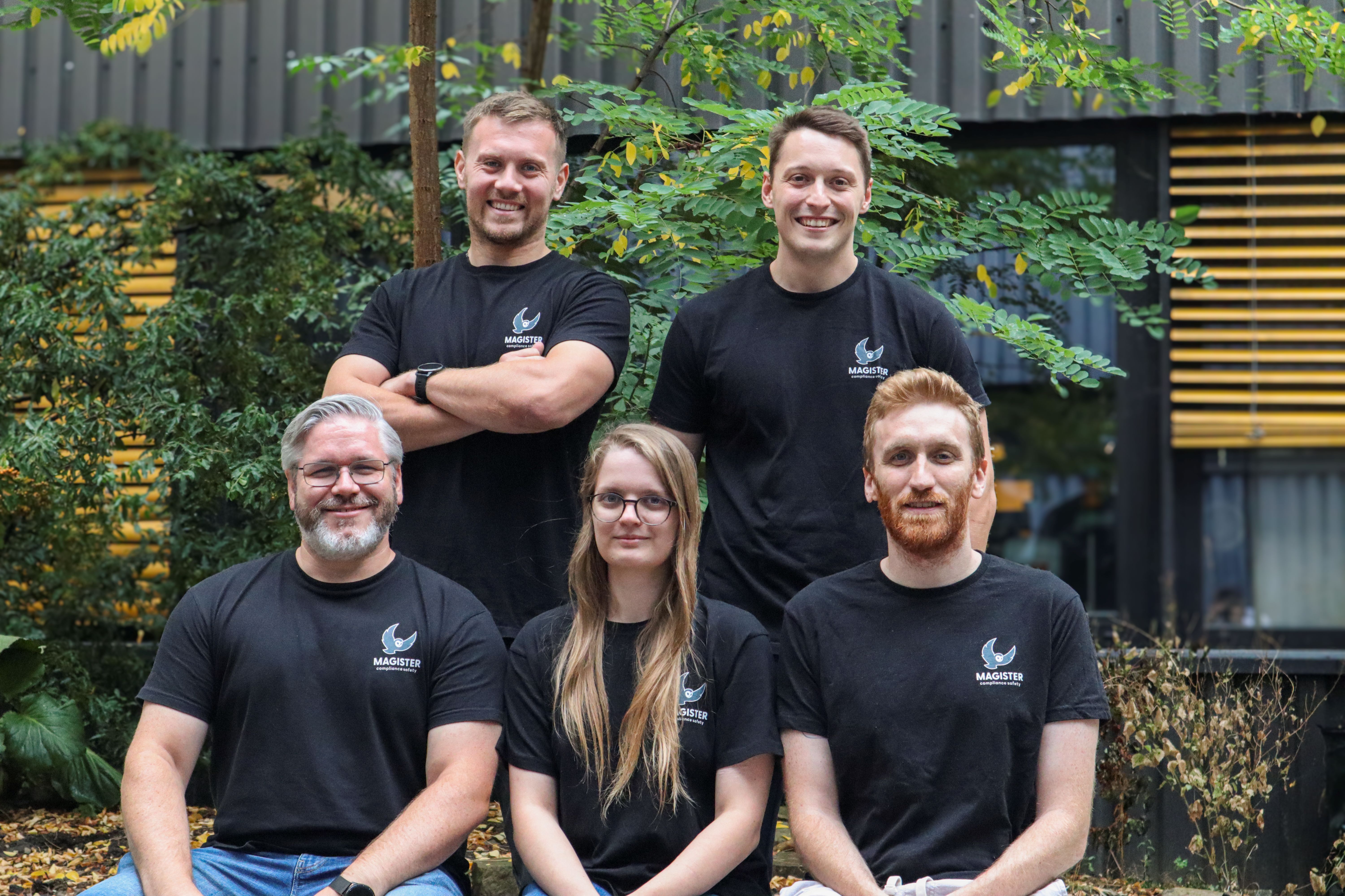 Vier Gründer und eine Mitarbeiterin tragen schwarze T-Shirts mit dem Firmenlogo und lächeln in die Kamera