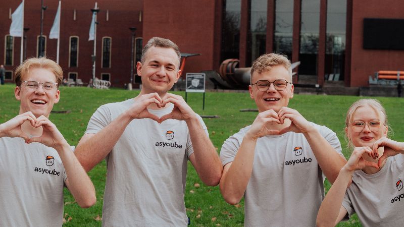 Die beiden Gründer und ihre beiden Mitarbeitenden tragen T-Shirts mit dem Firmenlogo, formen Herzen mit ihren Händen und lächeln in die Kamera