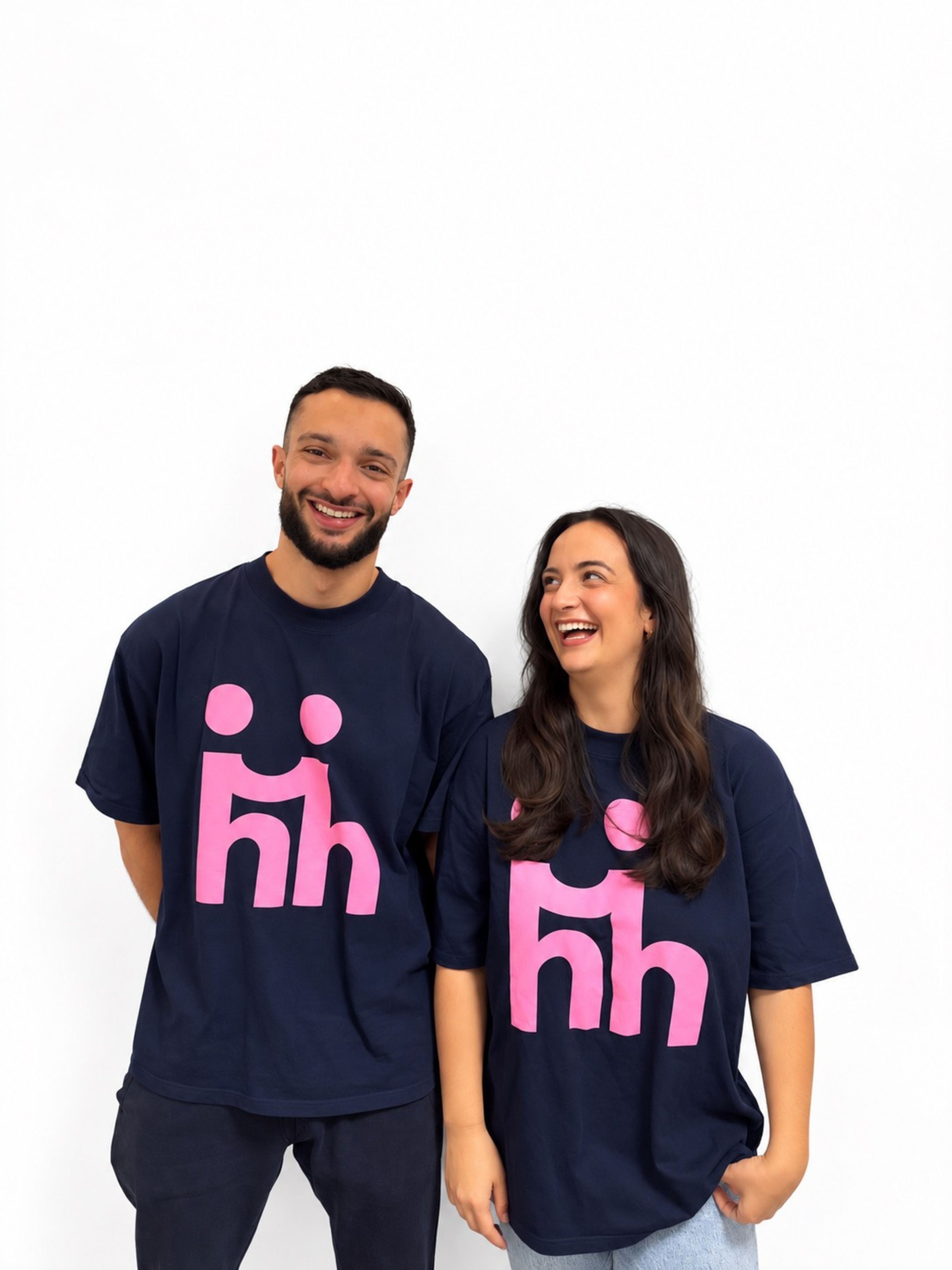 Hamdi Krichi und Anna-Luisa Raaf tragen jeweils ein T-Shirt mit pinkem Firmenlogo und lachen in die Kamera