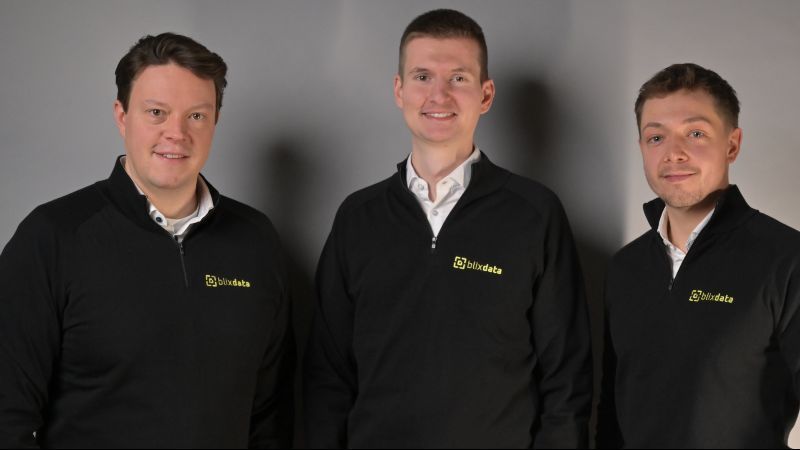 Der Gründer Nils Lüpke steht in der Mitte, rechts und links zwei Mitarbeiter. Alle drei tragen schwarze Sweatshirts mit dem Firmenlogoe
