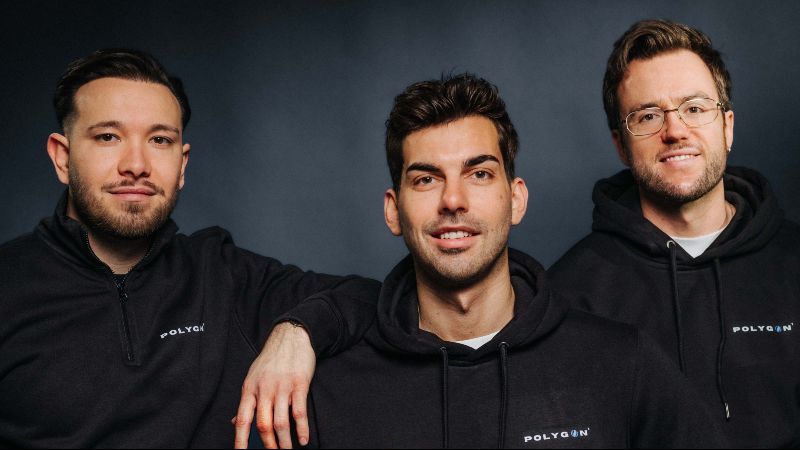 Die drei Gründer in schwarzen Hoodies mit Firmenlogo schauen in die Kamera