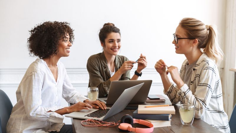 Drei Frauen sitzen zusammen an einem Tisch im Gespräch