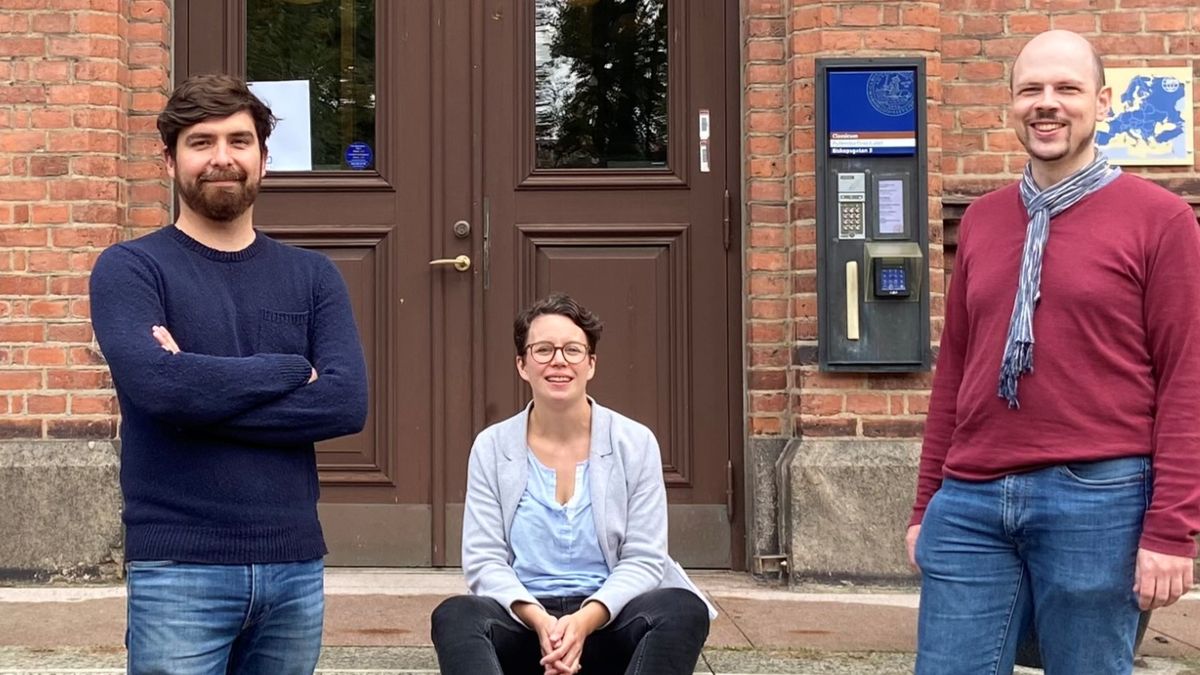 Die beiden Gründer rechts und links stehend, die Gründerin in der Mitte sitzend vor der Tür eines Hochschulinstituts