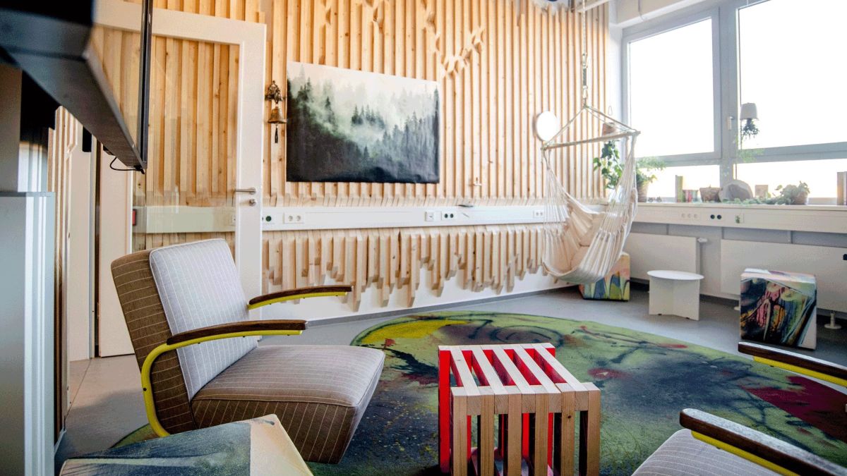 Ein legerer Sesssel in einem Raum mit einem großen Fenster und hellen Holzwänden.