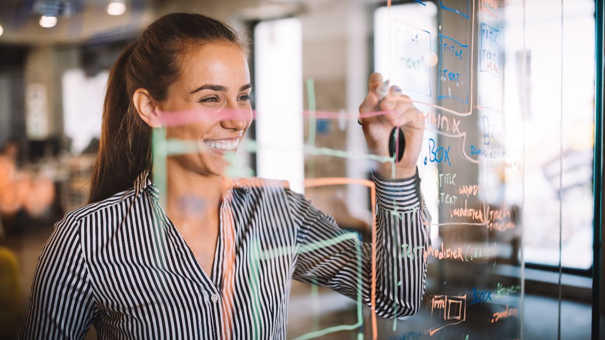 Junge Frau schreibt auf durchsichtigem Whiteboard