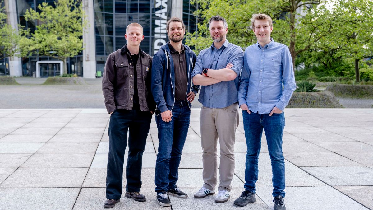Die vier Gründer stehen vor einem Gebäude der Universität und blicken in die Kamera