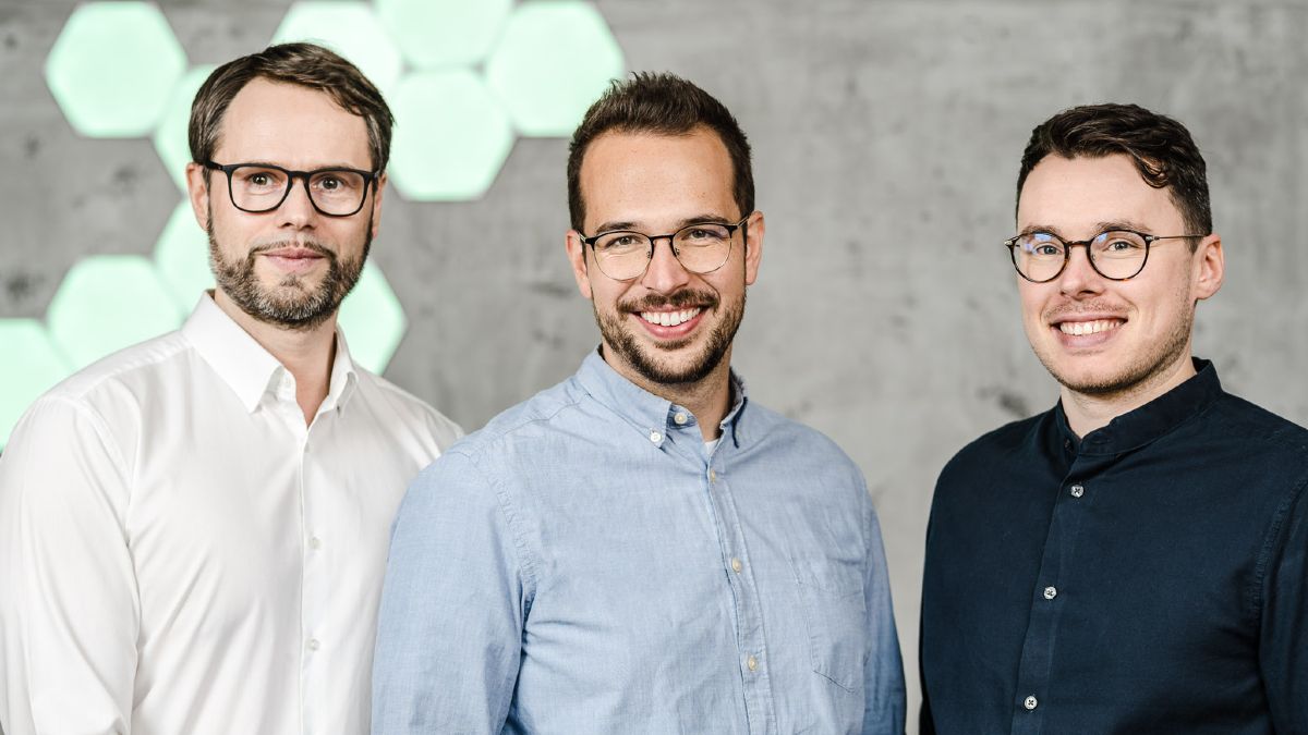 Die drei Gründer stehen nebeneinander und blicken lächelnd in die Kamera
