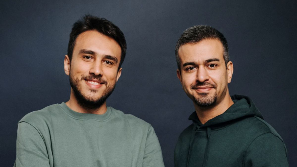 Zwei junge Männer um die 30 Jahre alt stehen nebeneinander und blicken in die Kamera